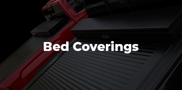 A red truck and a black truck with tonneau covers installed.
