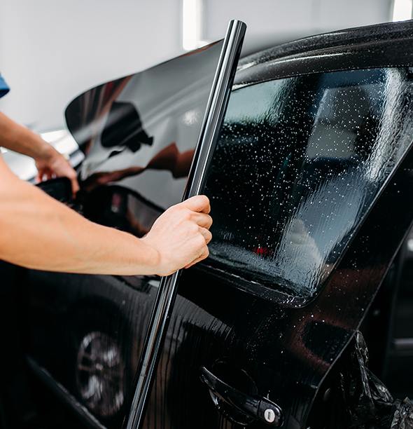 A car window tint, being applied to a black car.