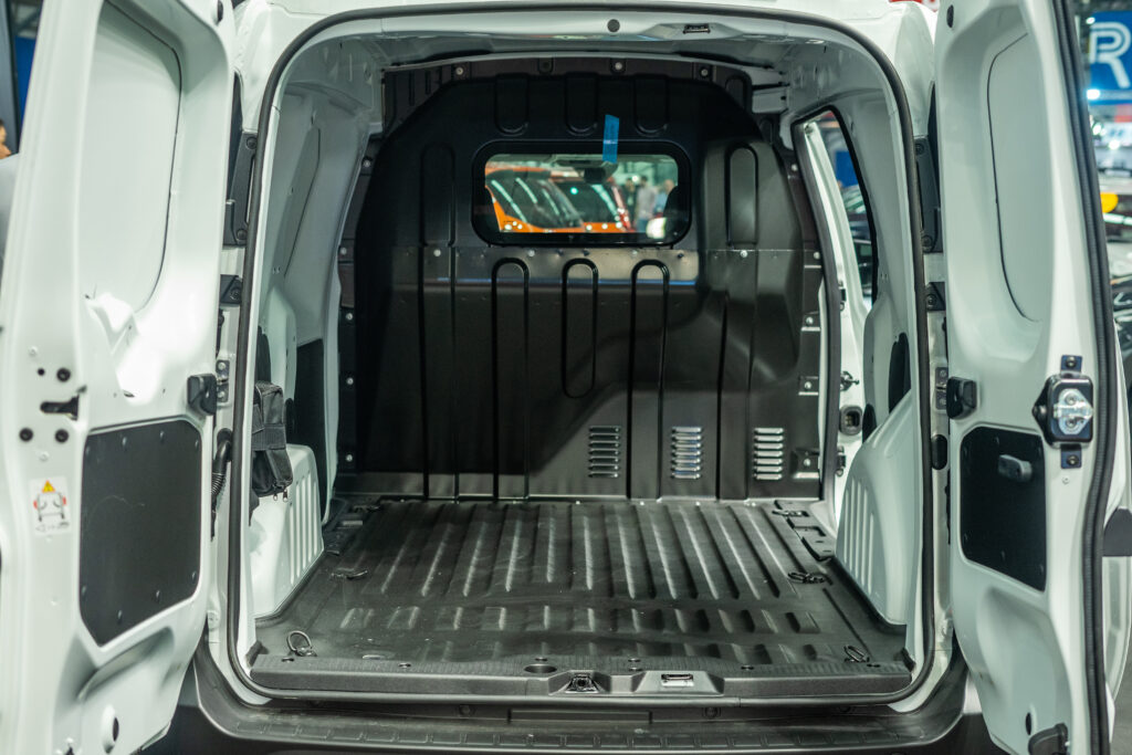 An empty trunk of a van. The floor is sprayed with protective lining, and there is a partition to separate the storage space from the driver.