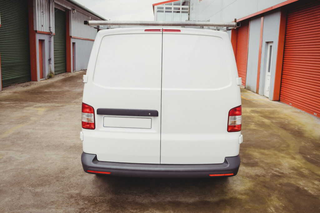 The rear doors of a white van in a commercial area.