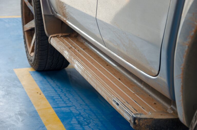 An image of a running board installed on a truck, outdoors in a parking spot.